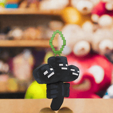 Load image into Gallery viewer, Minecraft 5 Inch Wither Bag Hanger Plush with pixelated design and clip, displayed in store.