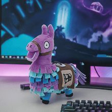 Load image into Gallery viewer, Fortnite Loot Llama 6 inch soft plush toy with vibrant colors and detailed stitching on a desk next to a keyboard and computer screen.

